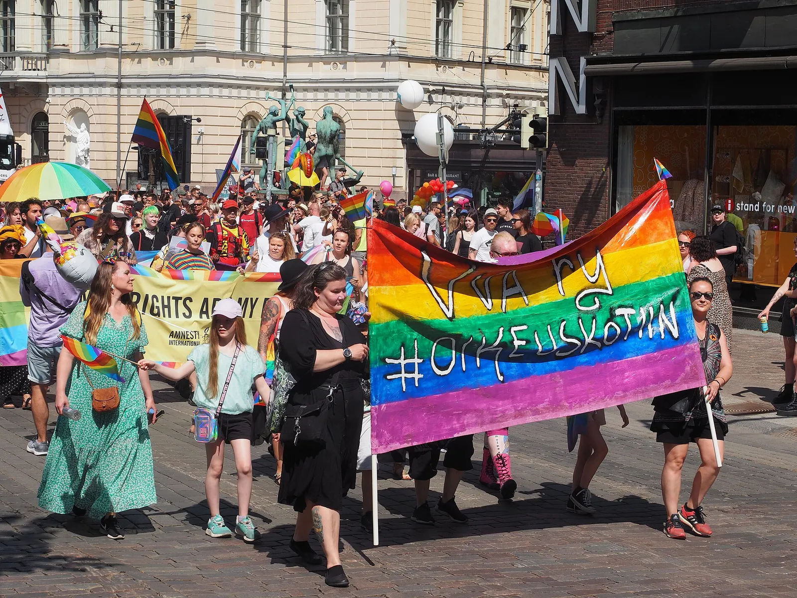 Helsinki Pride -kulkue etenee keskustassa sateenkaarilippujen kanssa